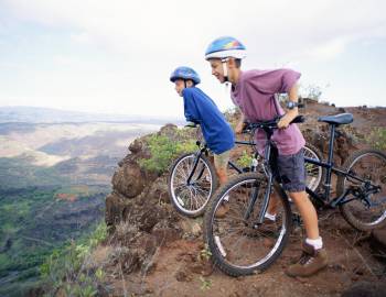 two boys on bikes in Hawaii overlooking a canyon