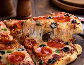 cheesy pizza slice getting lifted from pie