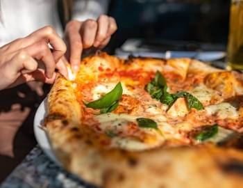 Person lifting a piece of pizza