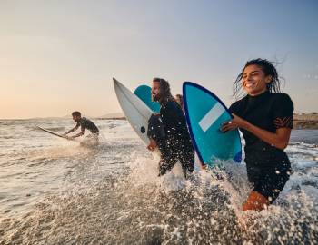 people running into the surf with their surfboards
