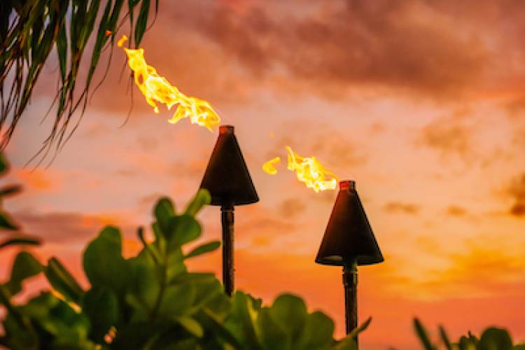 Hawaiian tiki torches lit at sunset