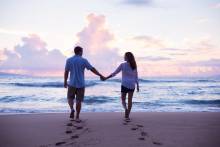 couple walking on beach, holding hands at suset