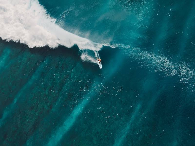 Surfer riding wave from above