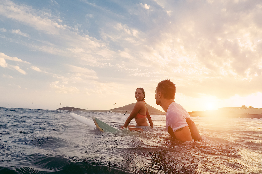 couple sitting on surf boards in the water