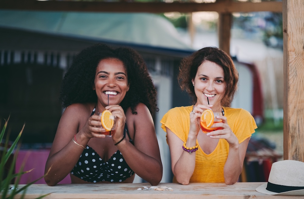two women enjoying cocktails at a tropical bar