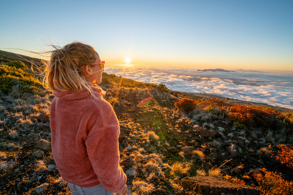 woman watching sunrise from mountain in Maui